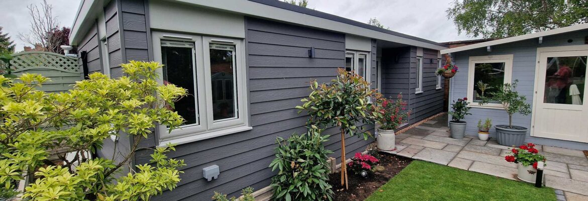 Dark grey annexe beside curved garden path and flower borders