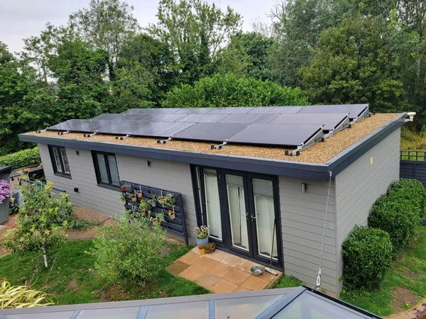 Grey-clad garden annexe near Northampton with solar panels on its flat roof and French doors opening onto a patio.